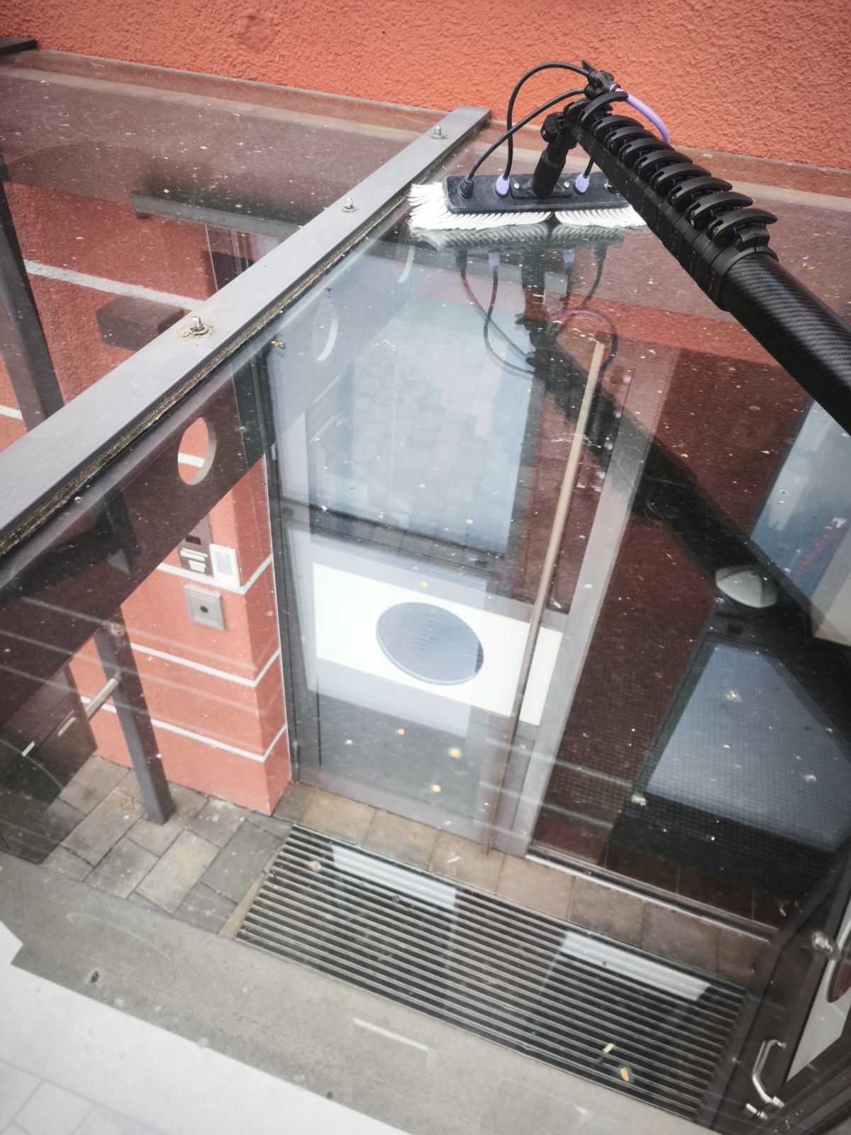 Glasreinigung im Eingangsbereich mit Teleskopstange